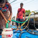 New-Delhi en Inde, 25 juin 2021 : une enfant remplit un bidon d'eau potable à l'aide d'un tuyau relié à un camion citerne.